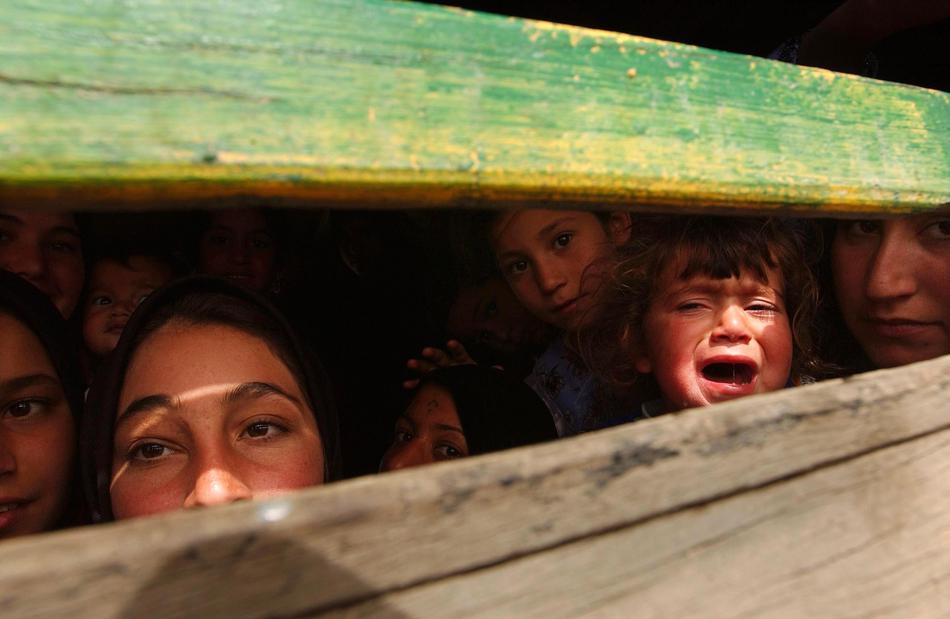 A family tries to leave the besieged Iraqi city of Basra March 31, 2003 in the back of a truck near a British manned bridge that had become a demarcation line. Photo by Spencer Platt/Getty Images.