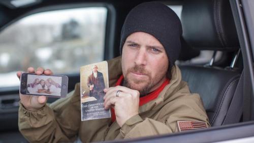 Oregon protestor, Jon Ritzheimer, displays a family picture on his phone and a copy of the Constitution to the media at the Malheur National Wildlife Refuge headquarters.  He needs bottled water and Ramen noodles, too.